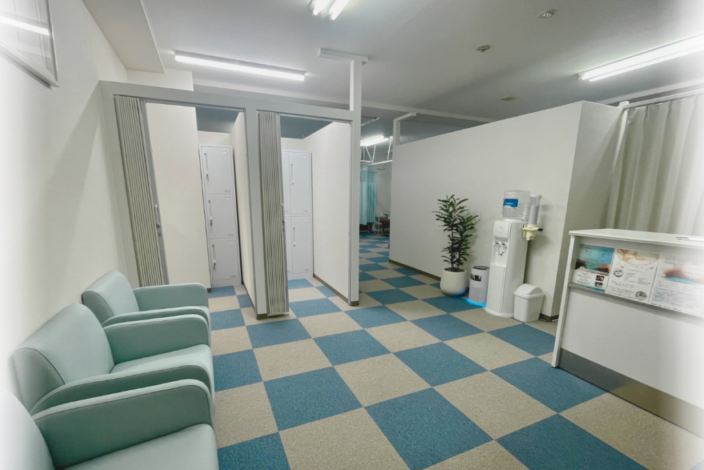 二ツ谷町整骨院の受付カウンターと、奥にある鍵付きロッカー付きの更衣室